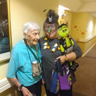 Two elderly women enjoying a festive moment together, dressed up for Halloween and surrounded by playful decorations.