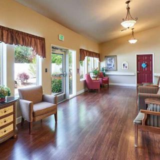 A cozy waiting room featuring chairs, wooden flooring, and natural lighting from large windows.