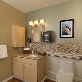 A modern bathroom with a sink, mirror, toilet, and wall art.