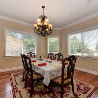 A cozy dining room with a chandelier, featuring a table set for four against large windows.