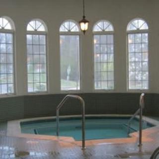 A serene indoor spa pool with large arched windows providing natural light.