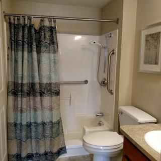 A clean and well-organized bathroom with a shower, toilet, and sink.