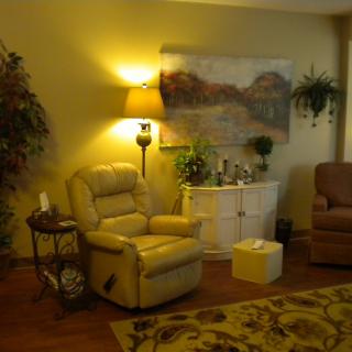 A cozy living room with a comfortable recliner, warm lighting, and decorative plants.
