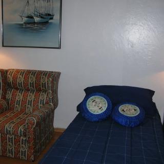 A cozy bedroom with a bed, patterned chair, and a painting on the wall.