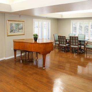 A spacious living room featuring a grand piano and a dining area with hardwood floors.