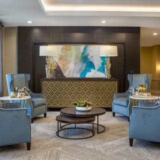 A modern living room with elegant armchairs, a central coffee table, and colorful artwork on the wall.