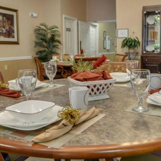 A well-arranged dining room table ready for guests, featuring elegant dinnerware and decorative elements.