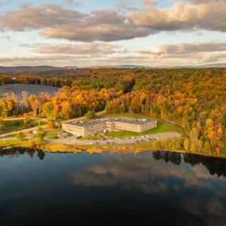 A picturesque aerial view of a serene lake surrounded by vibrant autumn foliage.