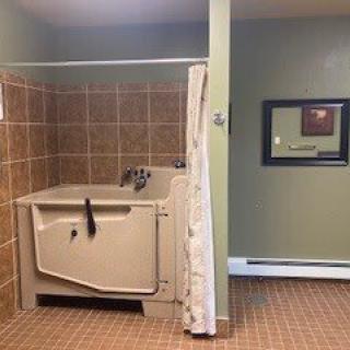 A bathroom with a bathtub and shower curtain, featuring tiled walls.