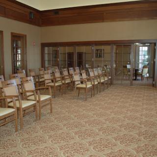 An empty meeting room featuring neatly arranged wooden chairs and a patterned carpet.