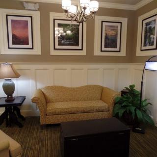 A cozy living room with a sofa, lamp, and framed artwork on the walls.