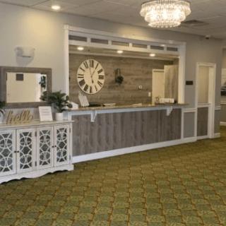 A warmly lit reception area featuring a large clock and elegant chandelier.