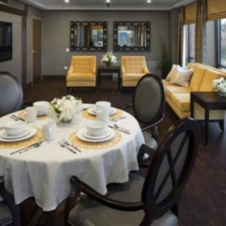 A stylish interior featuring a dining table set for four, with elegant chairs and a cozy living area with sofas and mirrors.