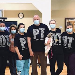 Dedicated physical therapy team posing together in their matching t-shirts.