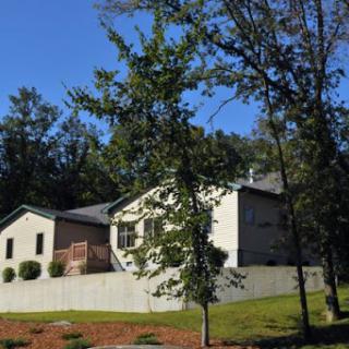 A peaceful residential house surrounded by greenery under a clear blue sky.