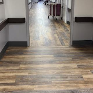 A view of a hospital corridor featuring wood-like flooring.