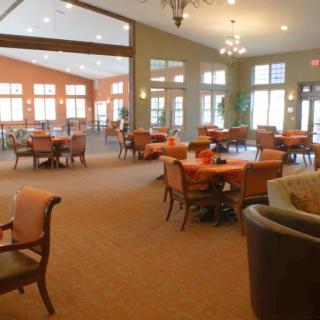 A spacious dining room with arranged tables and chairs, well-lit by natural light through large windows.