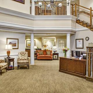 A spacious and elegantly designed lobby with a reception desk, comfortable seating, and a staircase leading to the upper floor.