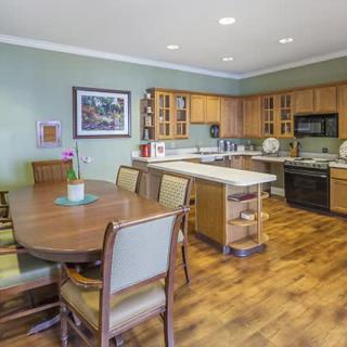 A modern kitchen and dining area with wooden cabinets, an island counter, and a large dining table.