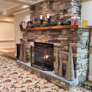 A cozy stone fireplace decorated with candles and holiday decor.
