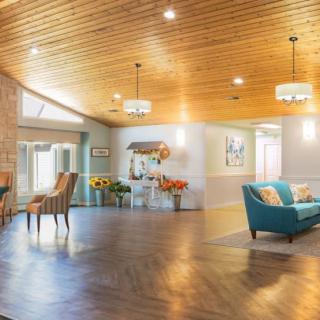 A spacious and cozy living room featuring a wood-paneled ceiling, stylish lighting, and comfortable seating arrangements.