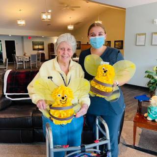 A joyful moment shared between a resident and a caregiver, both dressed in cheerful bee costumes.