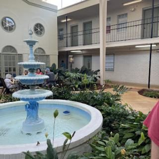 A serene courtyard featuring a fountain surrounded by lush greenery, creating a peaceful gathering space.