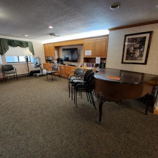 A spacious interior room featuring a piano, chairs, and wooden cabinets.