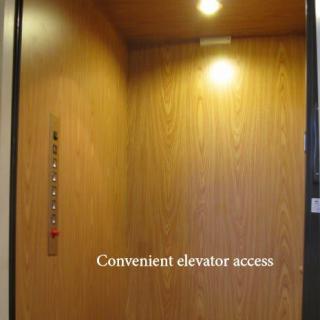 Interior view of an elevator with wooden paneling and ceiling lights.
