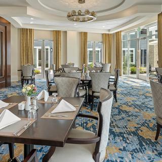 An elegant dining room with neatly arranged tables and chairs, featuring soft lighting and decorative elements.