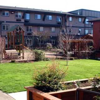A residential area featuring a landscaped garden and playground, surrounded by apartment buildings.
