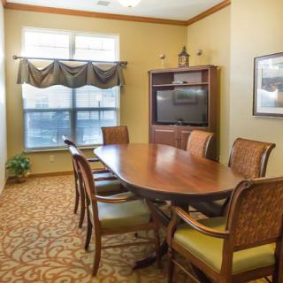 A cozy conference room with a wooden table, chairs, and a television.