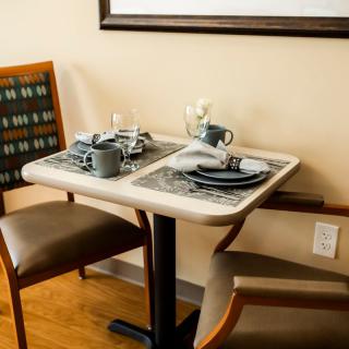 A cozy dining table set for two with cups and plates.