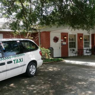 A taxi parked in front of a building, surrounded by greenery.