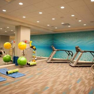 A modern gym with exercise equipment including treadmills, yoga mats, and exercise balls.