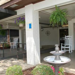 A cozy outdoor patio area with rocking chairs, a fountain, and lush hanging plants.