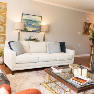 A cozy living room with a white sofa, decorative pillows, and a glass coffee table.