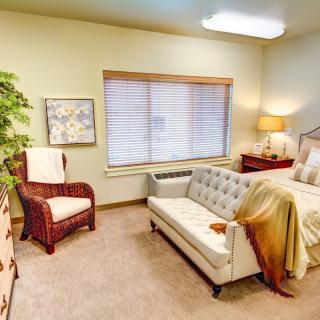 A cozy bedroom with a sofa and a comfortable bed beside a window.