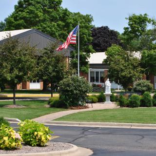 A building with an American flag, surrounded by a well-maintained garden and pathway.
