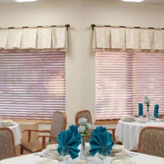 A neatly arranged dining area with decorated tables and window blinds.