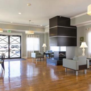 A modern lobby with comfortable seating, a central fireplace, and hardwood floors.