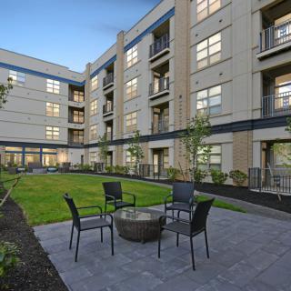 A modern apartment building with a central courtyard featuring outdoor seating.