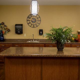 A contemporary kitchen with a central island, featuring a potted plant and a clock on the wall.