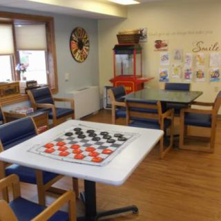A cozy game room featuring a checkers table, seating for board games, and a popcorn machine.