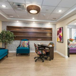 A modern office interior with stylish furniture, artwork, and a small lounge area.