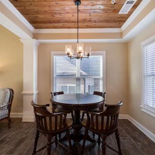 A cozy dining room with a round table and chairs, featuring a chandelier and tray ceiling.
