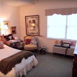 A cozy bedroom with a comfortable bed, armchair, and tasteful decor by the window.