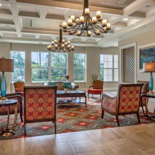 A spacious and elegant living room with comfortable seating and a large chandelier.