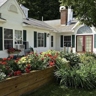A charming house with a vibrant flower garden in the front yard.
