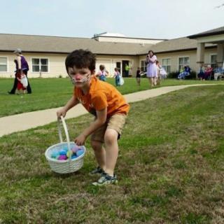 A child participates in an Easter egg hunt on a grassy lawn.